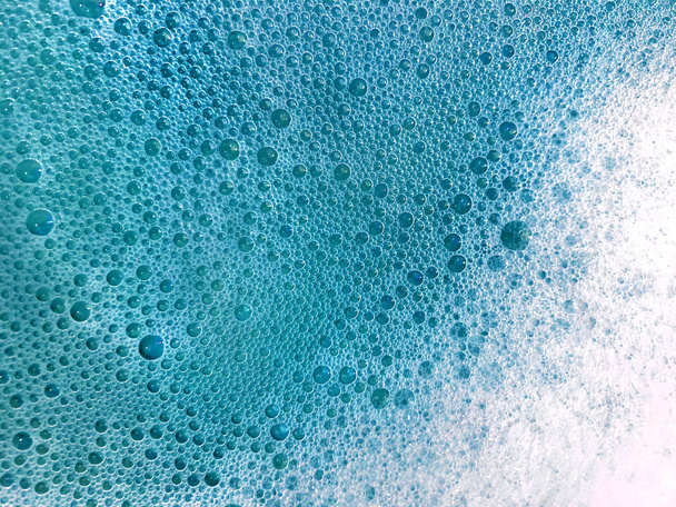 Fondo con espuma de jabón blanco en agua brillante azul turquesa
 - Foto, imagen