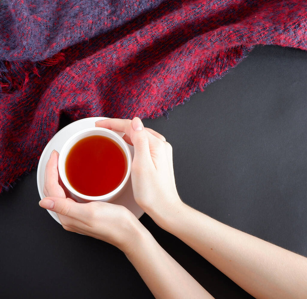 Hands holding a Cup of tea. On black background. Beautiful design background. Composition. - Foto, immagini