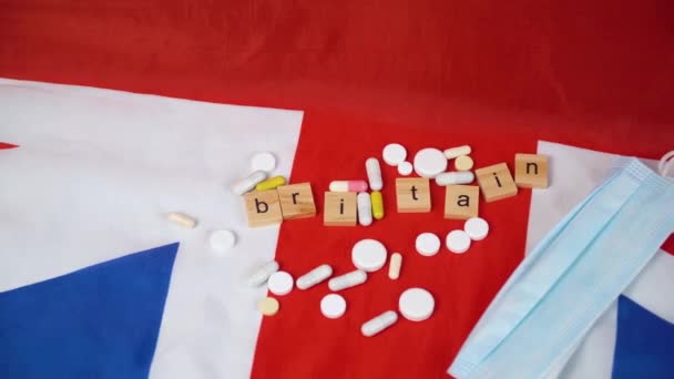 Mixed pills with blue protective mask on UK flag with the inscription Britain. UK healthcare - Кадри, відео