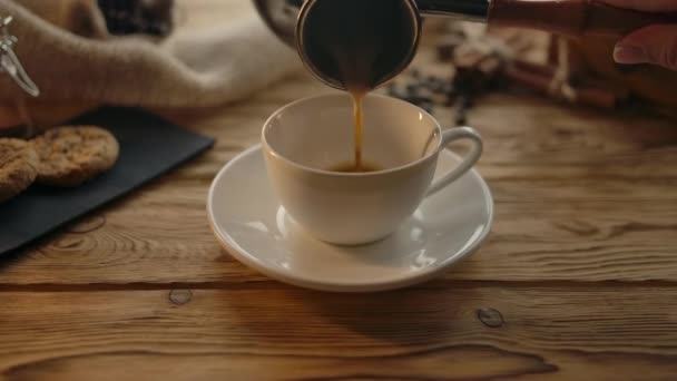 Wlewanie kawy z cezve do kubka na drewnianym stole - Materiał filmowy, wideo