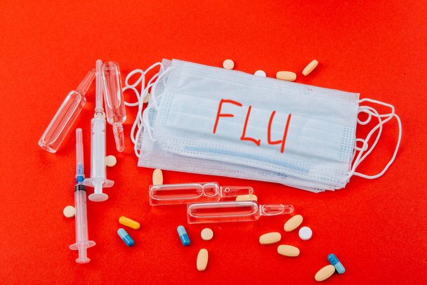 Protective medical mask with the inscription Flu on a red background.  - Foto, Imagem