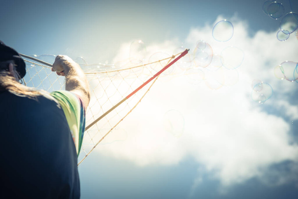 Por trás vista de bolhas fabricante artista fazendo bolha gigante no céu azul ensolarado nuvem na América
 - Foto, Imagem
