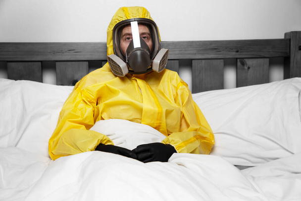 osoba, která se izoluje v posteli v ochranném obleku a masce - Fotografie, Obrázek