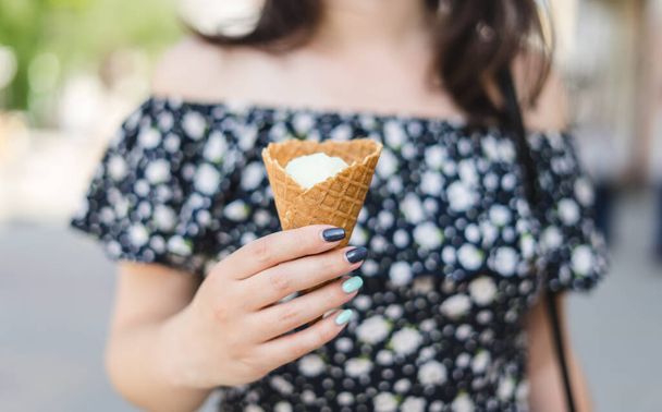 Joung woman holds vanilla ice cream in cone. - Foto, Imagen