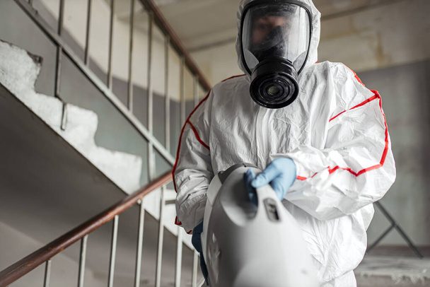 disinfector in protective suit conducts disinfection - Foto, Imagen