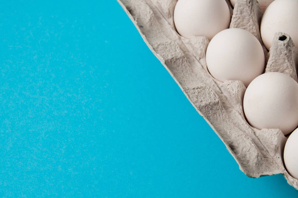 Eier in einem Tablett auf blauem Hintergrund. Konzeptfoto mit Platz für Text. - Foto, Bild