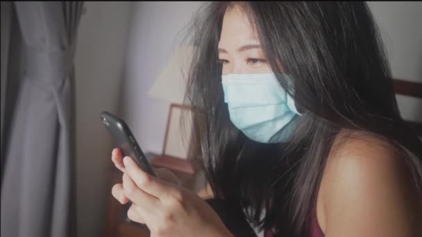 covid-19 quarantine home lockdown - young beautiful scared and overwhelmed Asian Chinese woman in protective mask checking online news worried about coronavirus pandemic - Metraje, vídeo