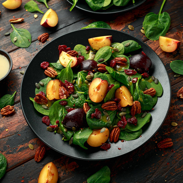 Veganský švestkový salát s brusinkami, dýňovými semínky, ořechy z ořechů, špenátem a hořčičným dresinkem - Fotografie, Obrázek