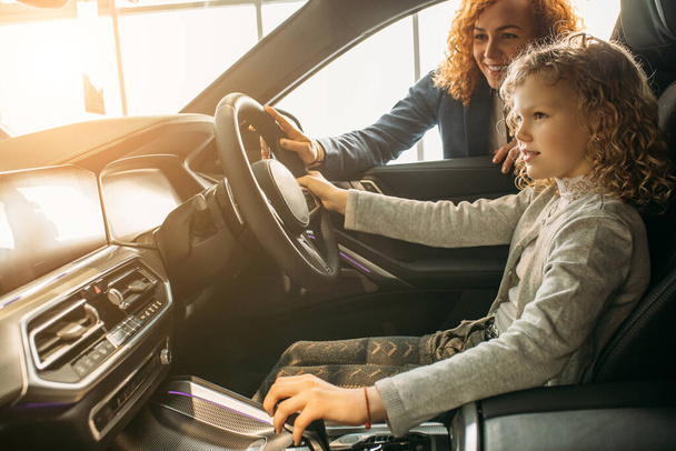 awesome curly caucasian child girl sit inside of new car - Foto, imagen