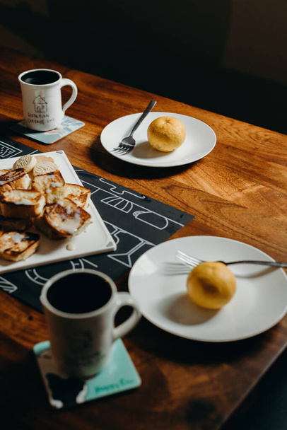 Ajuste de mesa para el desayuno Placa, tenedor, taza y tostadas en la mesa de madera
. - Foto, imagen