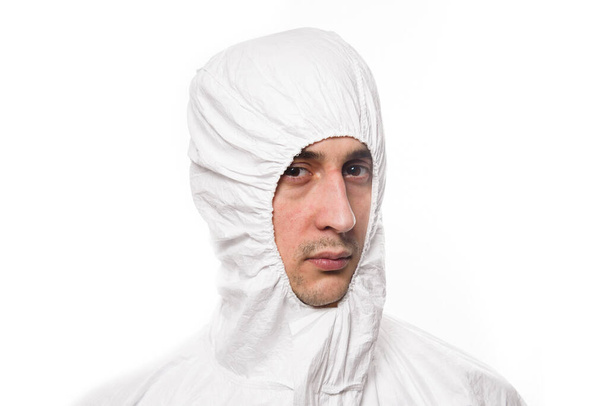 Портрет молодого человека в защитной белой медицинской форме во время пандемии коронавируса. Эпидемия, пандемия ковида коронавируса 19
. - Фото, изображение