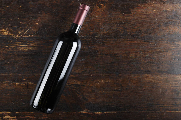 Closed bottle of wine on a brown wooden background. place for text. bottle without labe - Foto, afbeelding