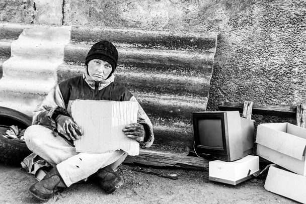 Koditon likainen nainen istuu pyytäen ohikulkijoita apua
 - Valokuva, kuva
