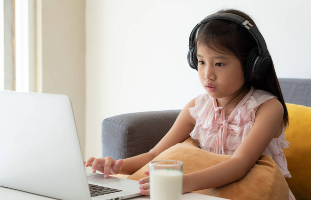 Een Aziatisch meisje studeert online cursus via computer als een home school student. sociale afstand, isolatie, quarantaine, covid-19, coronavirus, medisch, technologie, onderwijsconcept - Foto, afbeelding