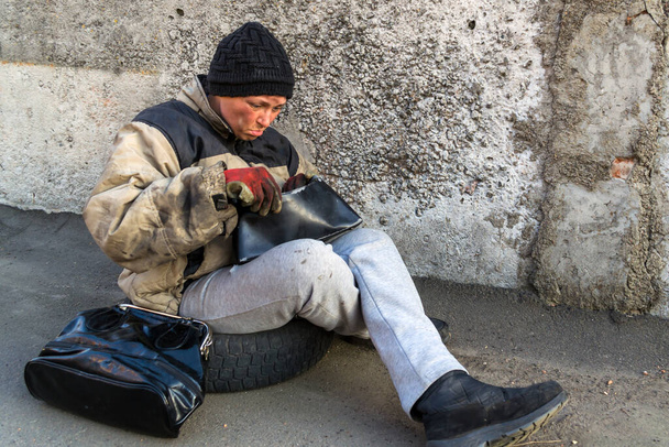 Бездомна брудна жінка рада, що знайшла сумку і перевірила знахідки
 - Фото, зображення