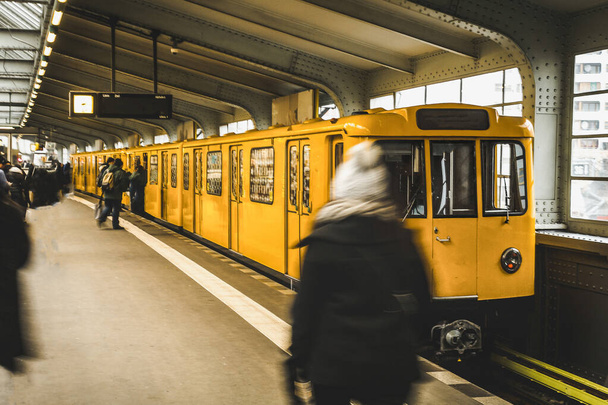 U-Bahnhof in Berlin mit gelbem Zug und Fahrgästen. Öffentlicher Nahverkehr in Berlin. Reisen und Tourismus in berlin concept. - Foto, Bild