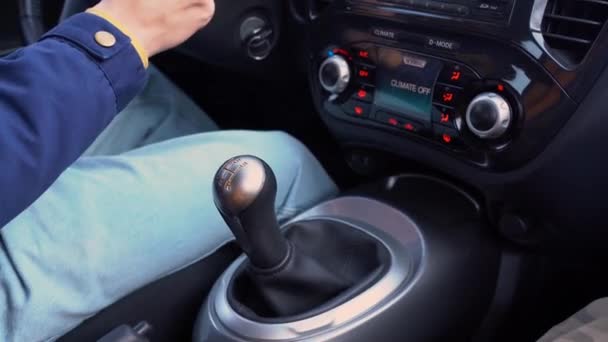 Чоловіча їзда, зміна передач. Рука водія в синьому піджаку переміщує ручне спорядження в автомобілі з кліматичним контролем. Парень управляє автомобілем і перемикачем передач, вмикає 1 передачу, потім 2-й, 3-й. - Кадри, відео