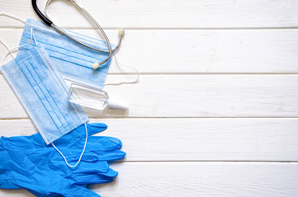 medical set. Protective blue medical mask, blue gloves, antiseptic spray and stethoscope lie on a white background - Photo, Image