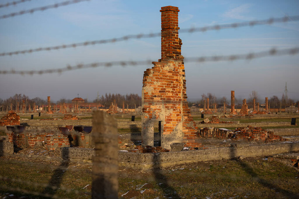 Auschwitz- Birkenau, Poland - 6 Decemeber 2019: електричний паркан з колючим дротом, зруйновані бараки в німецькому концтаборі Аушвіц II Біркенау, Бжезинка - Фото, зображення
