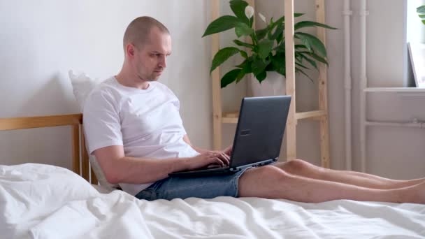 4k Man working office work remotely from home on bed. Using computer. The call to stay home safe. Distance learning online education and work. - Video, Çekim