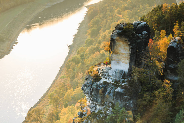 Rivierloop van de Elbe in het nationaal park van Saksen in de herfst. Rotsen met stenen en bossen in de zon in het Saksische Zwitserland. Zonsondergang aan de horizon boven de Elbe vallei - Foto, afbeelding