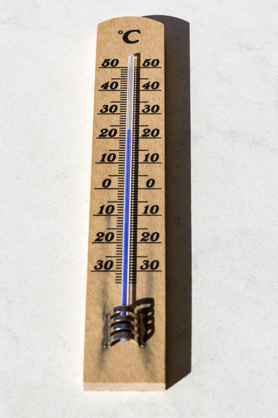 Vista de un termómetro en verano y primavera. El foco está en más de 20 grados Celsius. El termómetro está hecho de madera y viejo
. - Foto, imagen