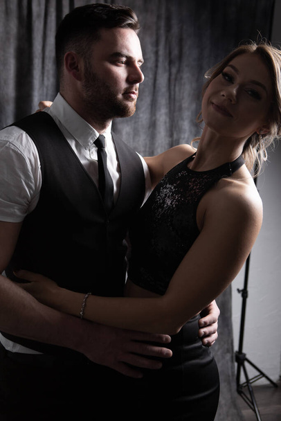 Hugging a beautiful man and a woman with light hair in a dark Studio under a counter light - Fotó, kép