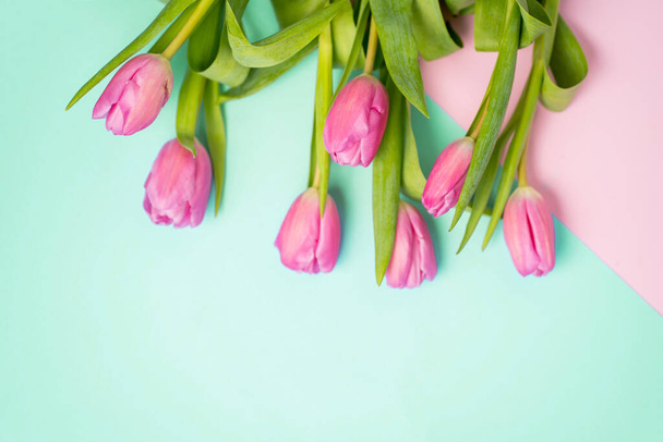 Closeup top view of a bouquet of pink tulips on a multicolored paper background with a copy space - Photo, image