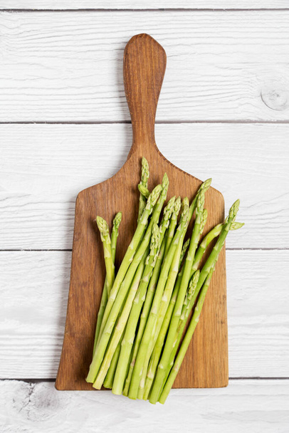 Asparagus on cutting board at white wood background. Top view, flat lay, lay out, copy space for text. - Φωτογραφία, εικόνα