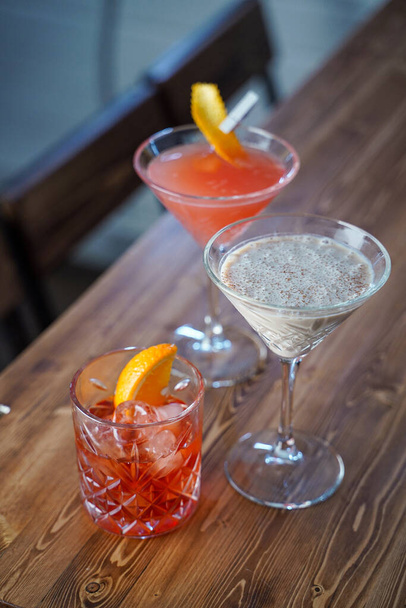 Сливочный коктейль, негрони и косметический загар на деревянной барной стойке в лофт-баре
 - Фото, изображение