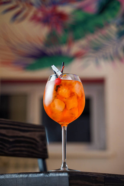 Aperol spritz cocktail with ice and orange on tropical background in a bar - Fotó, kép