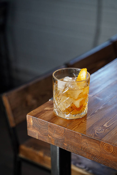 Klassieke ouderwetse cocktail met bourbon en whisky op houten tafel in een neon light bar - Foto, afbeelding