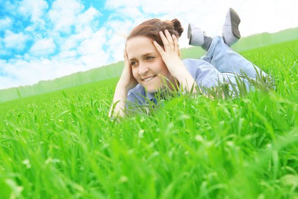 Smiling girl portrait, lying in grass field. Outdoor.  - Фото, изображение