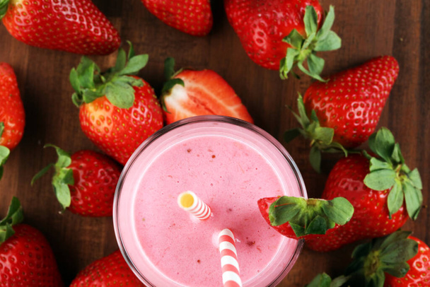 Glass of fresh strawberry shake, smoothie or milkshake and fresh strawberries on table. Healthy food and drink concept with juicy fruits  - Photo, Image