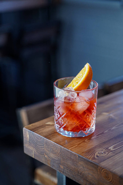 Bitter citrus negroni on a wooden bar counter in pink neon lights - Фото, изображение