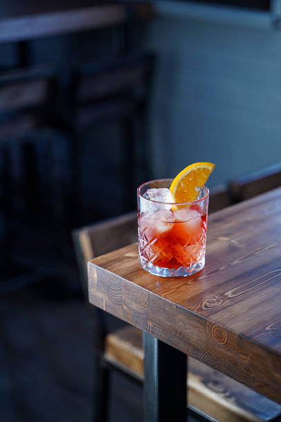 Bitter citrus negroni on a wooden bar counter in pink neon lights - Photo, Image