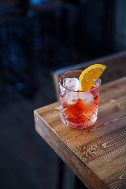 Bitter citrus negroni on a wooden bar counter in pink neon lights - Foto, afbeelding