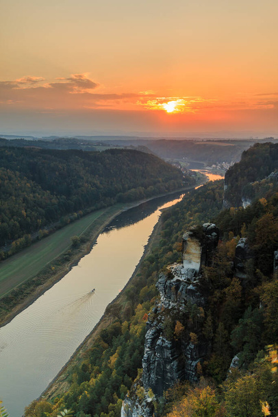 Saxon Switzerland with the Elbe valley in the evening. National park with a view from the Bastei bridge with the Elbe and rocks, trees and forests in the autumn mood with an orange horizon at sunset - Fotoğraf, Görsel