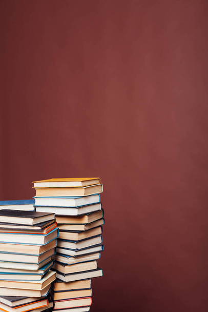 wiele stosów książek edukacyjnych do nauki przygotowania do egzaminów w instytucie na brązowym tle - Zdjęcie, obraz