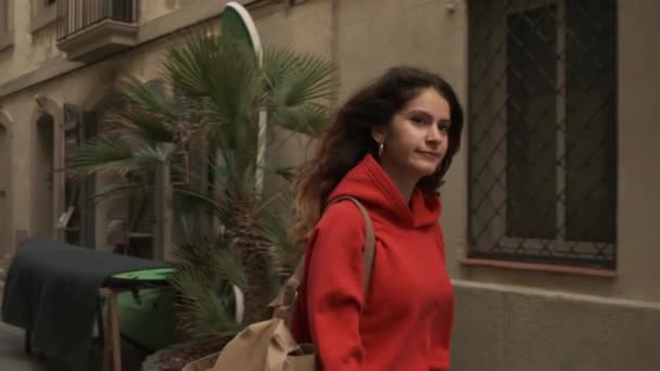 Charming ισπανόφωνη κοπέλα με σακίδιο ονειρικά περπάτημα κατά μήκος άνετο δρόμο της πόλης και μόνο - Πλάνα, βίντεο