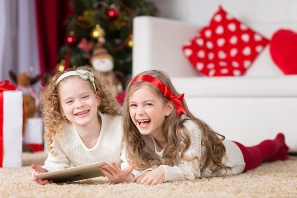 Noel, Noel, Noel, kış, mutluluk konsepti - tabletle oynayan iki sevimli kıvırcık kız - Fotoğraf, Görsel