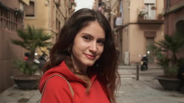 Retrato de la atractiva chica hispana morena coqueta mirando en cámara en la acogedora calle
 - Metraje, vídeo