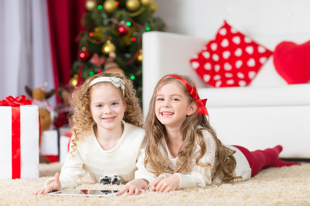Natal, x-mas, inverno, conceito de felicidade - duas meninas encaracoladas adoráveis brincando com tablet pc - Foto, Imagem