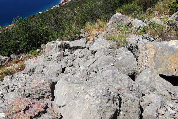 Rode hete stenen in onherbergzaam land in de provincie Split-Dalmatië, Kroatië. Deel van de natuur in de buurt van Brist en Gradac stad. Een lange wandeling door de stad. Vakantie in de bergen. - Foto, afbeelding