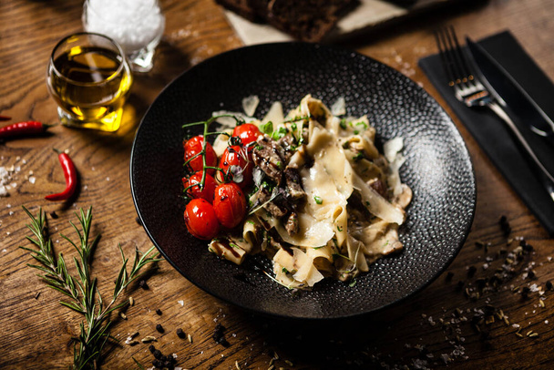 Black Angus Pasta served in a black bowl in restaurant - Photo, Image