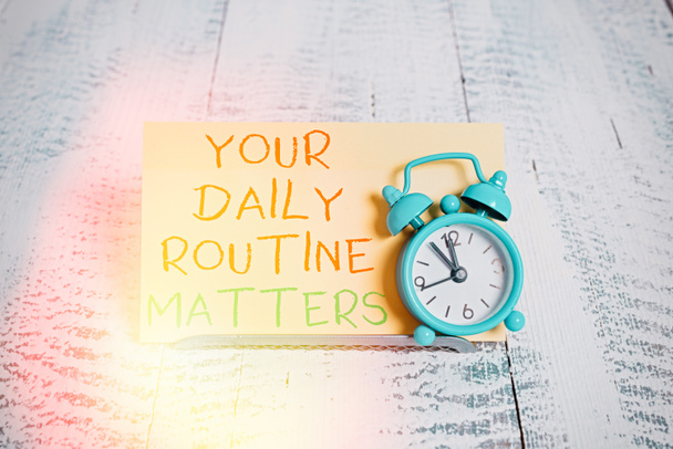 Word writing text Your Daily Routine Matters. Business concept for practice of regularly doing things in fixed order Mini blue alarm clock stand tilted above buffer wire in front of notepaper. - Photo, Image