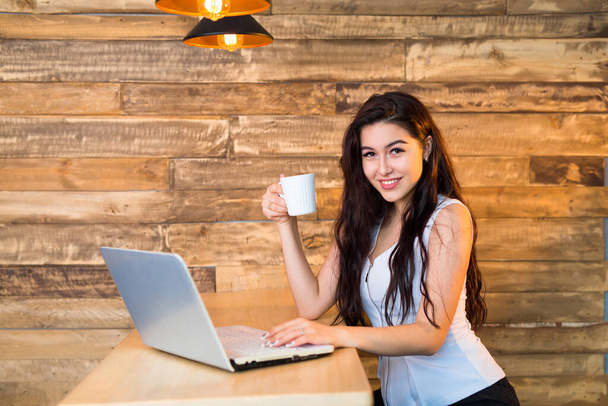 schöne junge Frau an einem Tisch mit einem Laptop - Foto, Bild