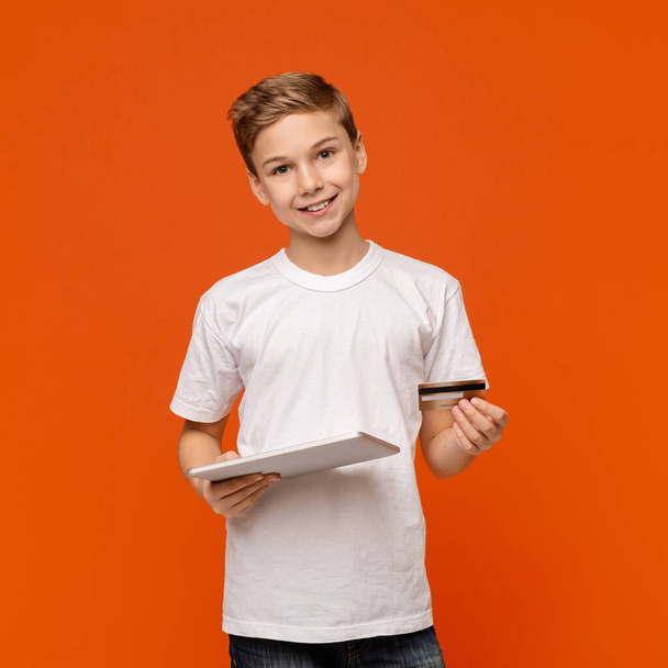 Adolescent mignon utilisant une tablette numérique et une carte de crédit
 - Photo, image