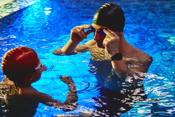 Dad and trainer teaches boy son to swim, have fun, play and splash in a blue swimming pool - Foto, Imagem