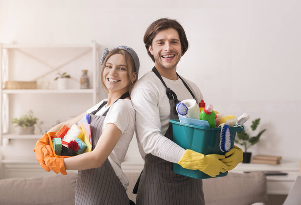 Couple posing at home with buckets of household supplies in hands - Фото, зображення